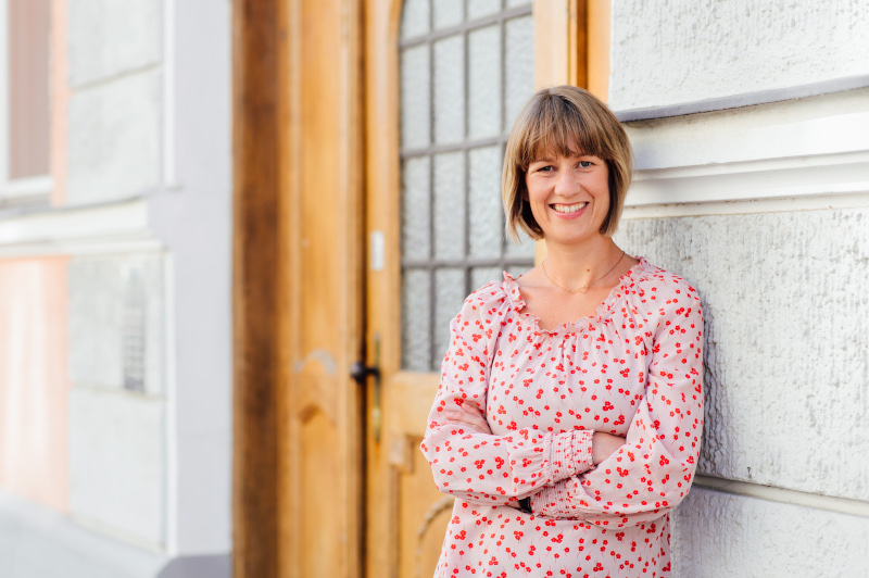 Regina mit verschränkten Armen an die Wand gelehnt
