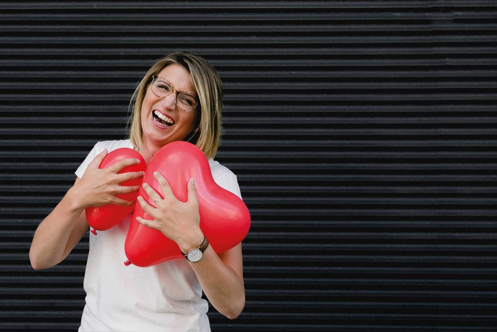 Frau mit Herzluftballons in den Armen