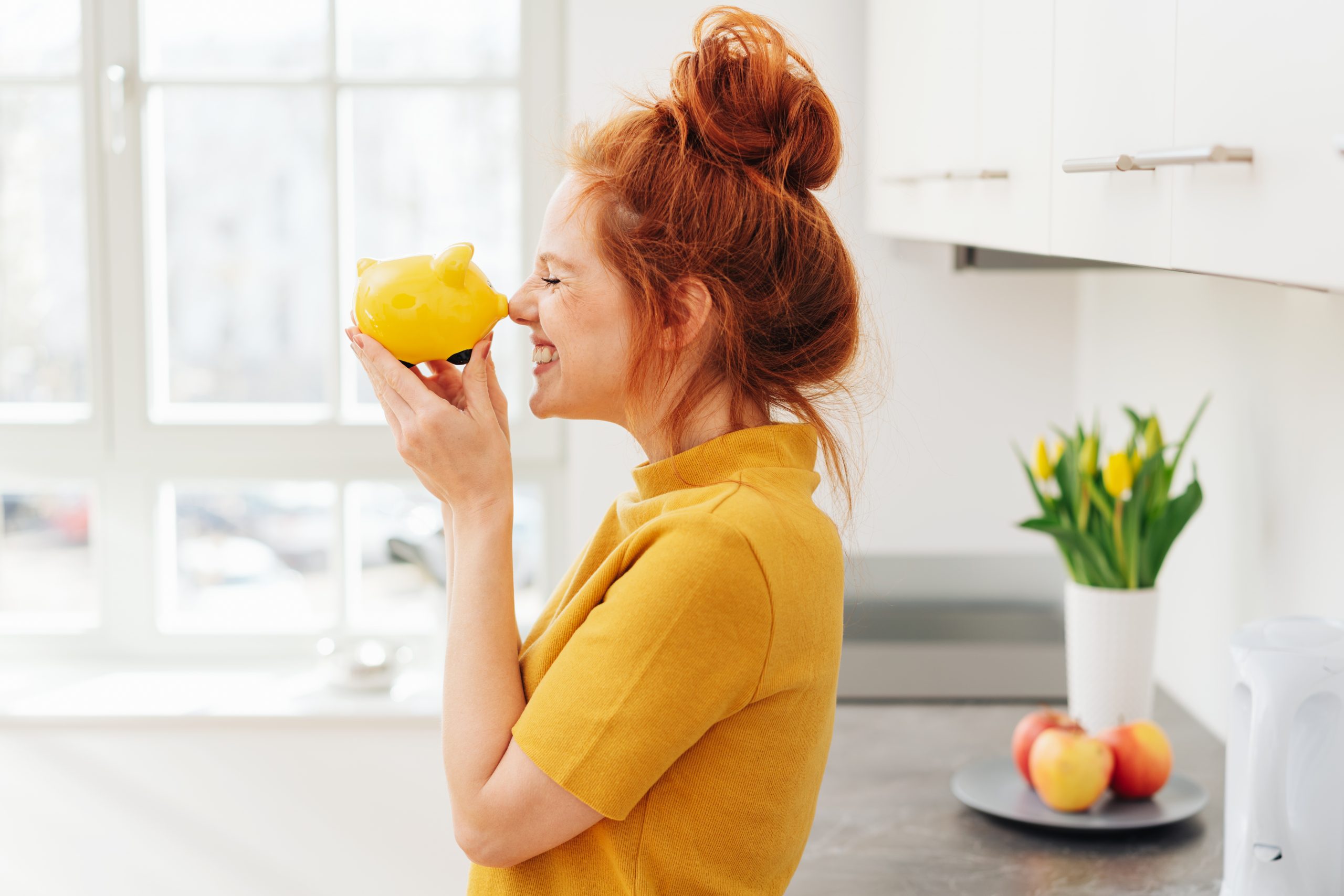 Smiling woman playing with piggy bank